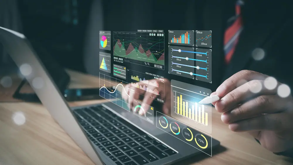 Pessoa usando notebook e segurando caneta digital em holograma de gráficos
