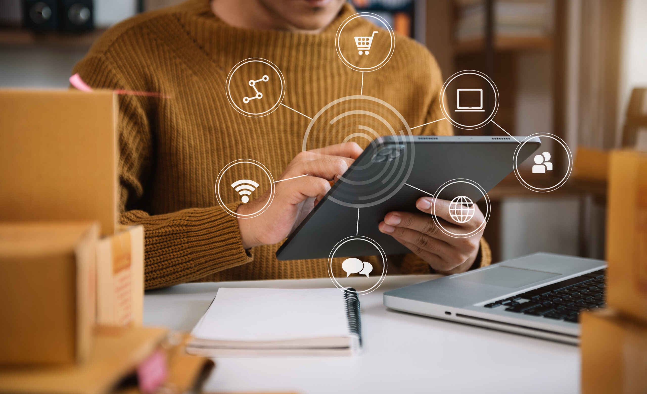 Pessoa utilizando tablet para gerenciar vendas online com ícones digitais ao redor, representando sincronizar estoque entre marketplaces e canais de e-commerce